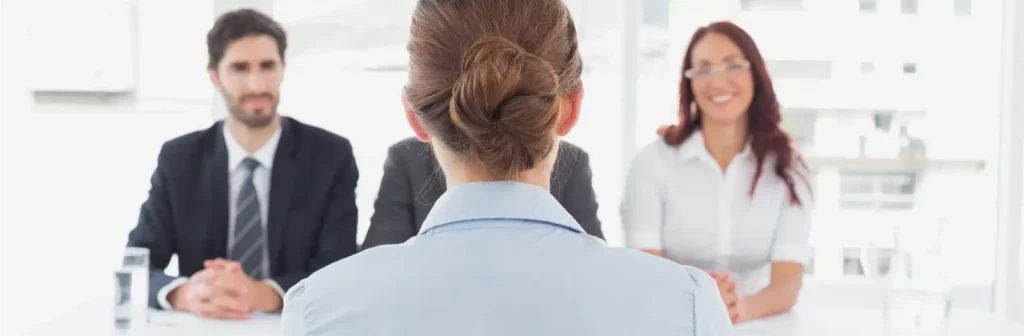 Eine Prüfungsteilnehmerin sitzt vor dem Prüfungskommitee aus drei Personen.